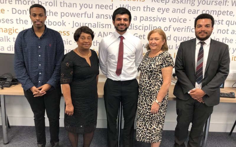 Standing in a line are Kamal Sultan wearing a blue shirt with his hands clasped in front of him, Baroness Lawrence in a smart black dress, Kumail Jaffer looking very smart in a white shirt with a red tie and a big grin, Sue Ryan wearing a leopard print dress and Courtney Bartlett looking very smart in a grey suit with a white shirt and striped tie. Baroness Lawrence and Sue Ryan are noticeably shorter than the men!