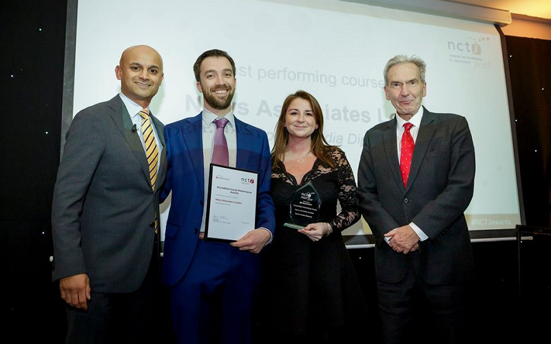 News Associates London head of journalism Graham Moody (centre left) and editorial development manager Lucy Dyer (centre right) collecting the awards for top overall  NCTJ course and top fast-track course at the NCTJ Awards for Excellence 2019 with Sky Sports News presenter Dharmesh Sheth (left) and NCTJ chairman Kim Fletcher (right). Graham and Lucy are smiling and holding NCTJ awards.