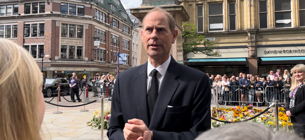 A close up of Prince Edward in a black suit talking to the public in Manchester.