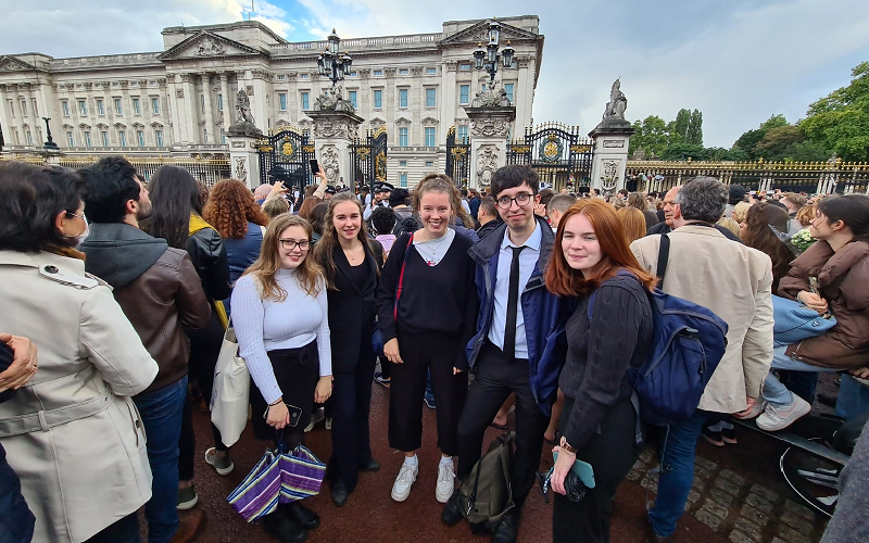 News Associates trainees gather reaction of Queen Elizabeth II's death at Buckingham Palace. From left to right you can see Heather Nicholls, Jasmine Laws, Olivia Christie, Max Kendix and Rachel Duffy standing among a crowd of people in front of the palace.