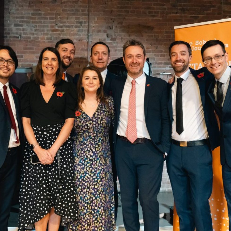 A group photo of the News Associates training team, including Paul, Alice, Kieran, Phil, Lucy, James, Graham and Tom. The photo was taken at graduation 2023 so everyone is dressed up and looking happy.