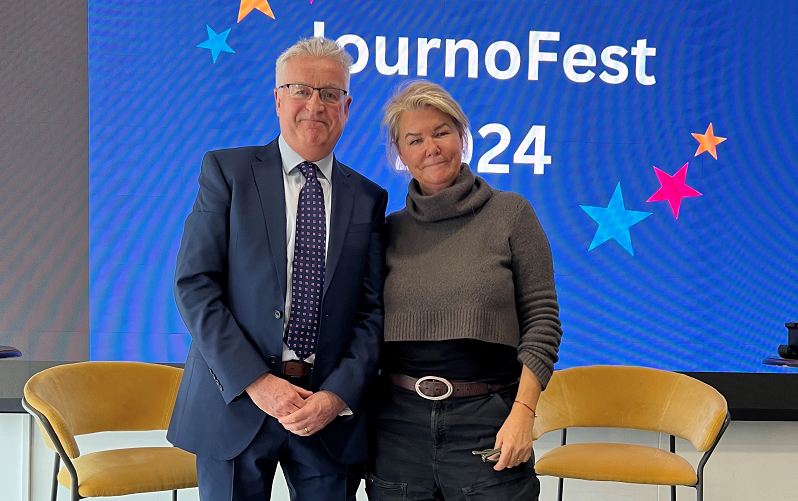 News Associates deputy managing editor Graham Dudman with Sky News special correspondent Alex Crawford after her Q&A at JournoFest 2024. They are standing and smiling in front of a blue screen with the words JournoFest 2024.
