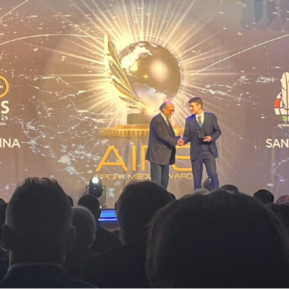 Jack Bantock on stage collecting his award from AIPS President Gianni Merlo at the ceremony in Spain
