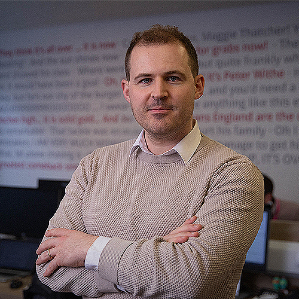 Photo of News Associates media law tutor Charlie Moloney posed in the newsroom with his arms crossed.