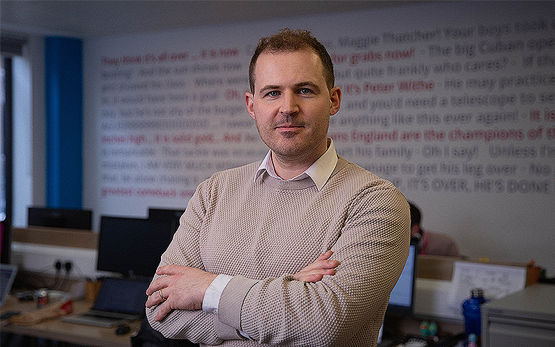 Photo of News Associates media law tutor Charlie Moloney posed in the newsroom with his arms crossed.